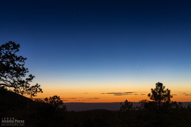 Ein kleiner schwacher Komet in einem Dämmerhimmel mit einer Wüstenlandschaft im Vordergrund.