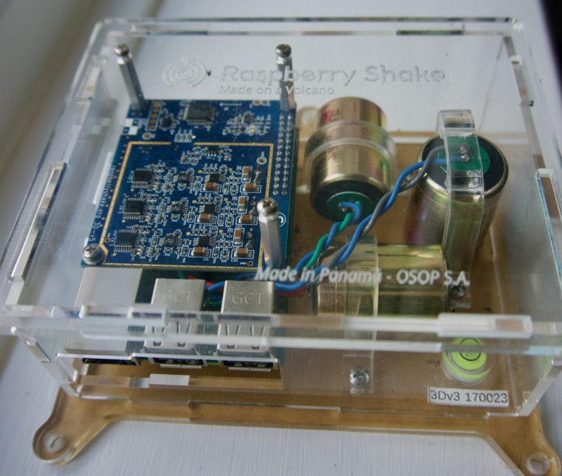 Clear plastic box containing electronics and two cylinders at right angles.