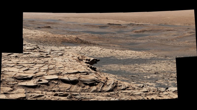 Layer of tan yellow sandstone on top of grayer land.