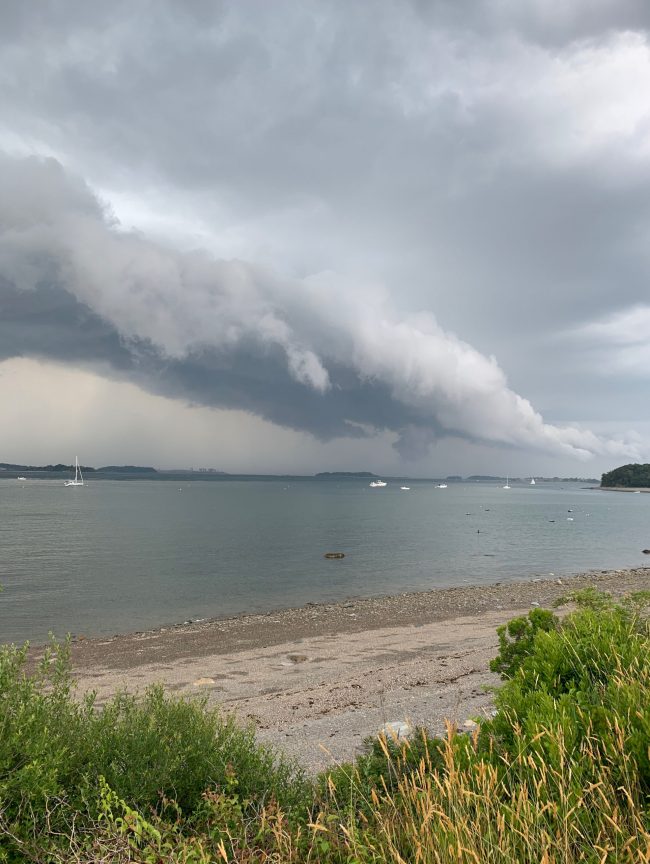 Long, flat linear cloud over gray water.