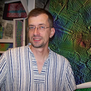 Smiling man in eyeglasses and striped shirt.