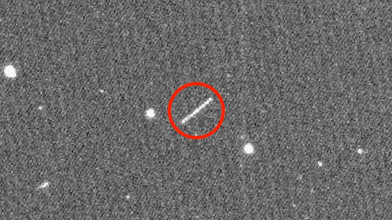 A red circle around a short white line on a gray background spotted with white dots.