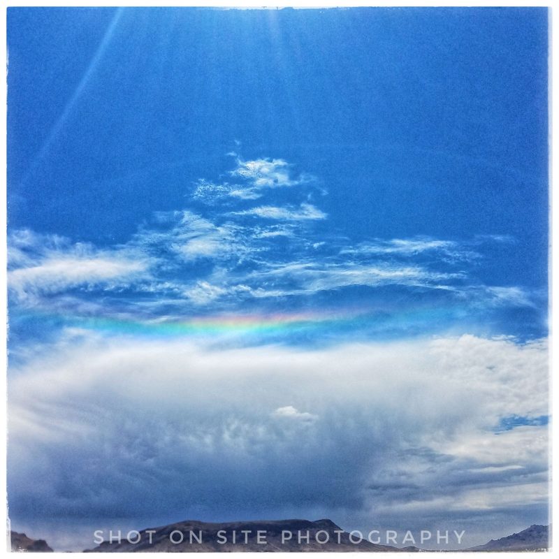 Circumhorizon arc over a ridgeline, with the sun just out of view at the top of the image.