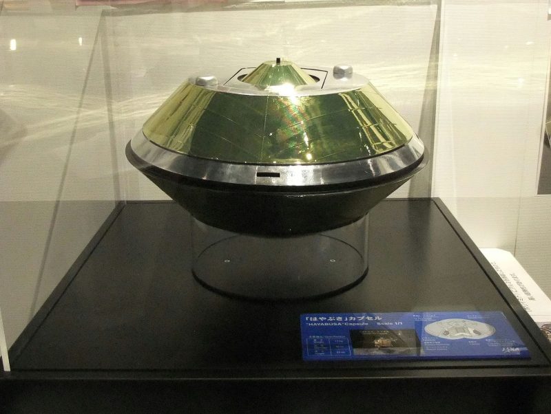 A 'flying saucer' shaped capsule, inside a glass display case.