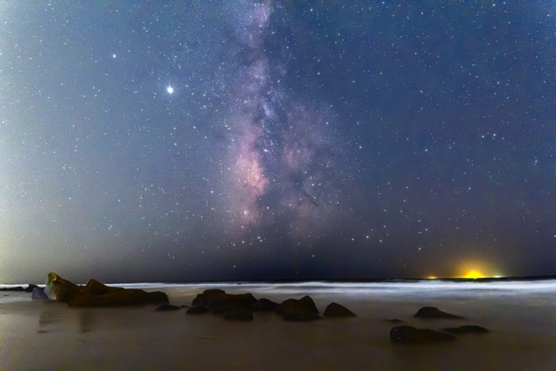 Edgewise view of the summer Milky Way, soaring straight up from the horizon, on a dark night.