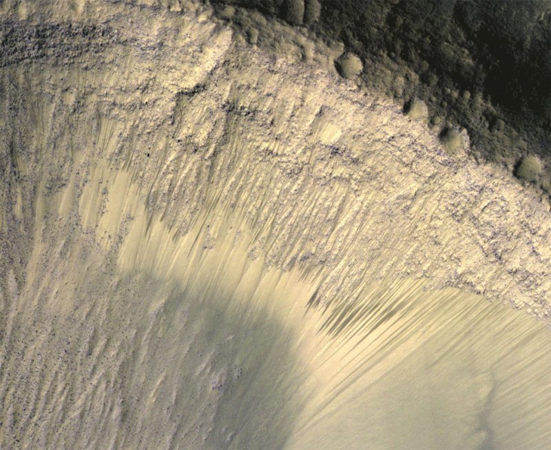 Long, thin and straight dark streaks on a steep rocky slope.