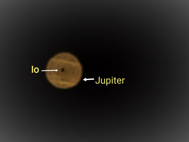 Fuzzy, banded Jupiter, with Io's dark dot-like shadow in the middle, with labels.