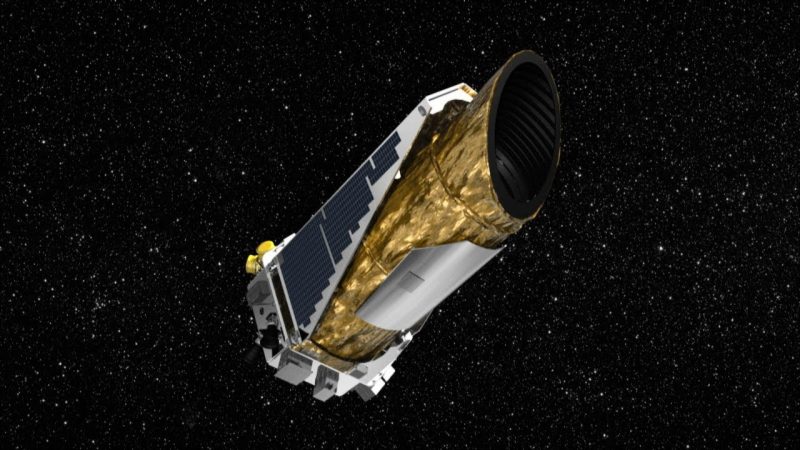 Cylindrical gold-foil-covered telescope satellite in space with stars in background.