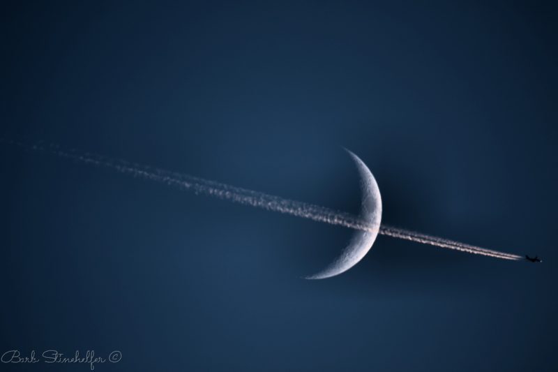 Waxing crescent moon, perfectly bisected by a jet and its long, straight, narrow contrail.