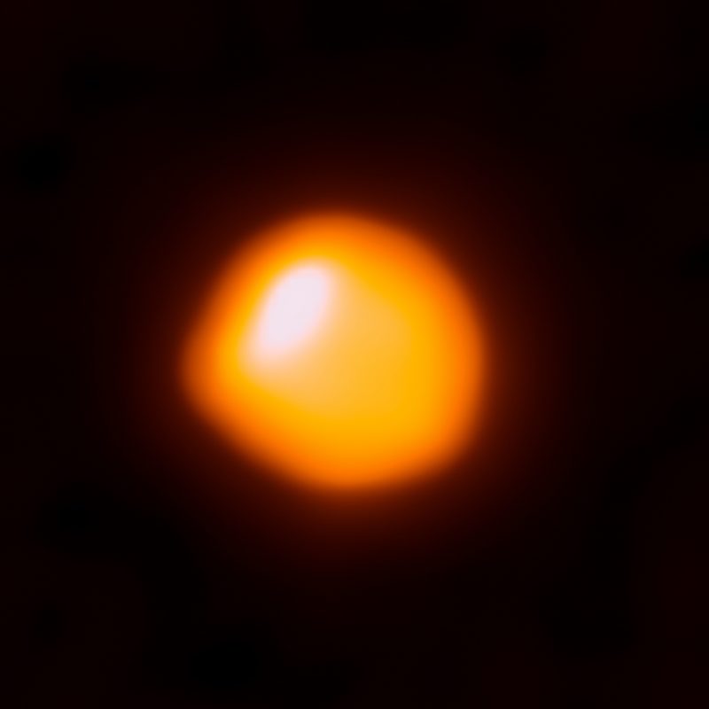 Bright red-orange blob with white spot on it, on black background.