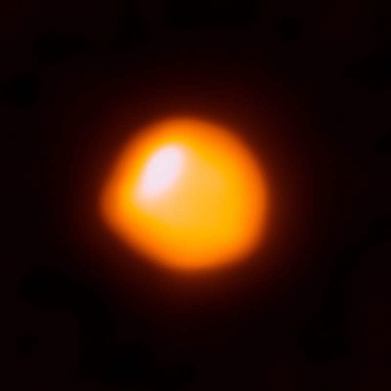 Bright orange-red spot with a white spot and a bump on a black background.