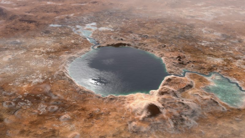 Circular lake with small river in brownish-reddish terrain.