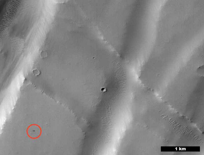 Context Camera image showing dunes and craters on Mars with small crater identified as a black speck in lower left.