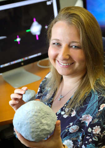 A young blonde woman holding a 7-inch 3-D printed model of Psyche.