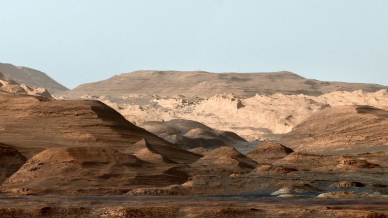 Layered hills, some with flat peaks, with blue skies in the background.