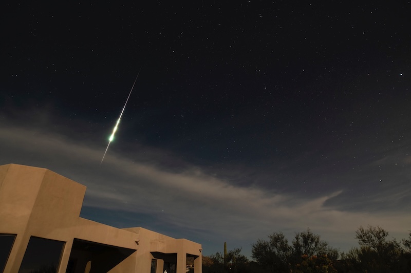 Bright Taurid meteor streaking downard in a dark sky.