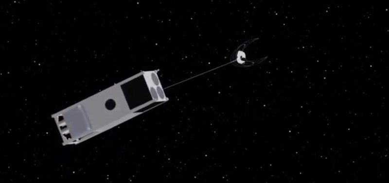 A boxlike spacecraft in orbit with a line going to a piece of space debris, against a black background.