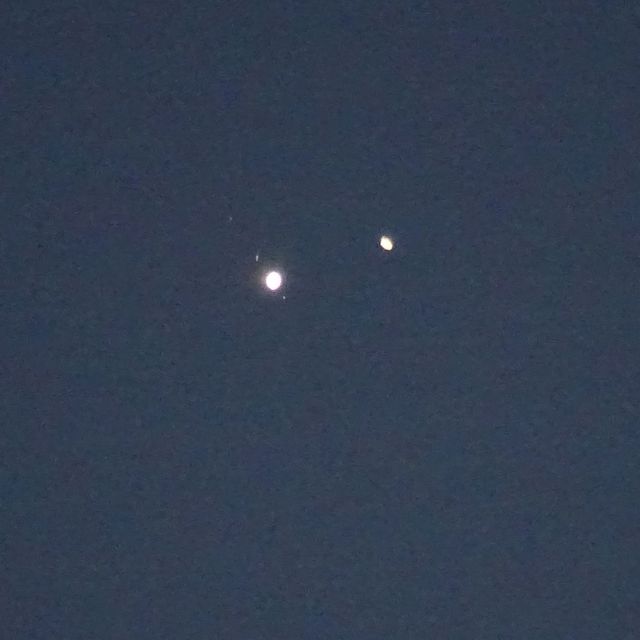 Two bright dots on blue gray background, largest dot with a few more faint ones on two sides.