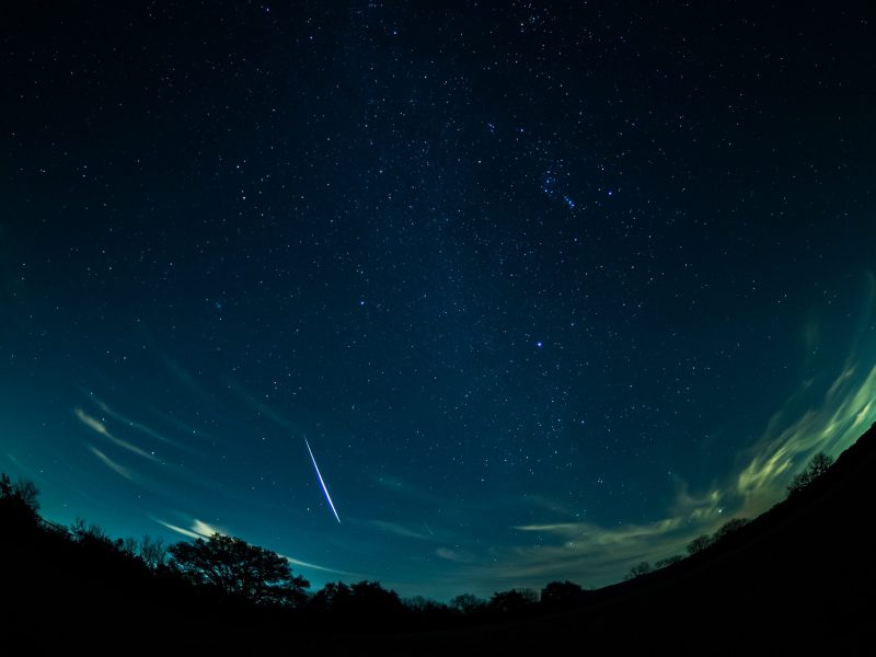 A bright Geminid streaks across the night sky.