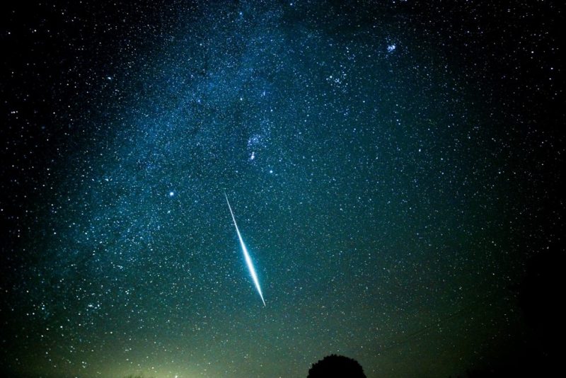 Very bright, nearly vertical streak in densely starry sky.