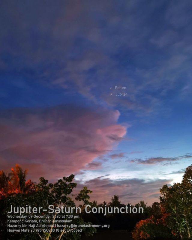 Sunset sky with clouds and 2 bright planets, treetops in foreground.