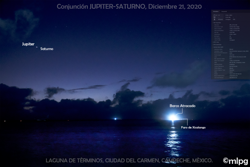 Bright dots of Jupiter and Saturn with a boat docking across a body of water under a deep blue sky.