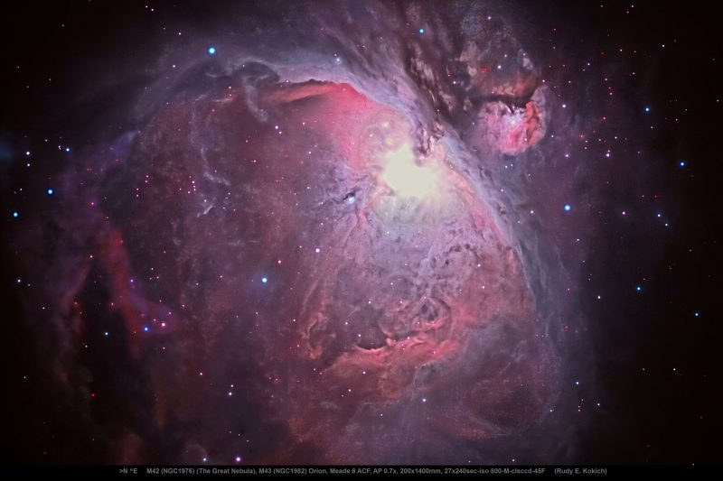 Orion Nebula in the shape of a cave made of pink and purple gasses with bright light at center.