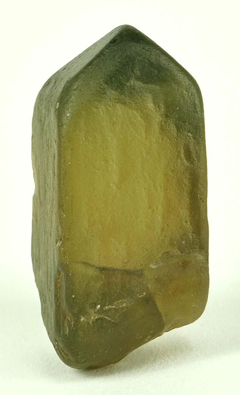 A zircon shaped mostly like a rectangle except that the top is pointed. The entire crystal is olive-green.