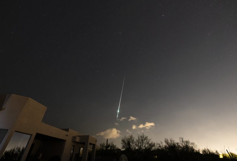 Thin, vertical barely greenish streak with a slight bright white bulge along it, in a grayish sky.