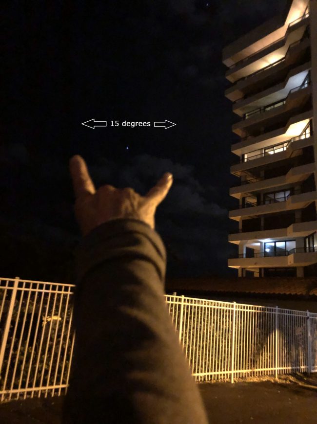 View along arm with hand with fingers extended. From pinky to index finger, measures 15 degrees of sky.