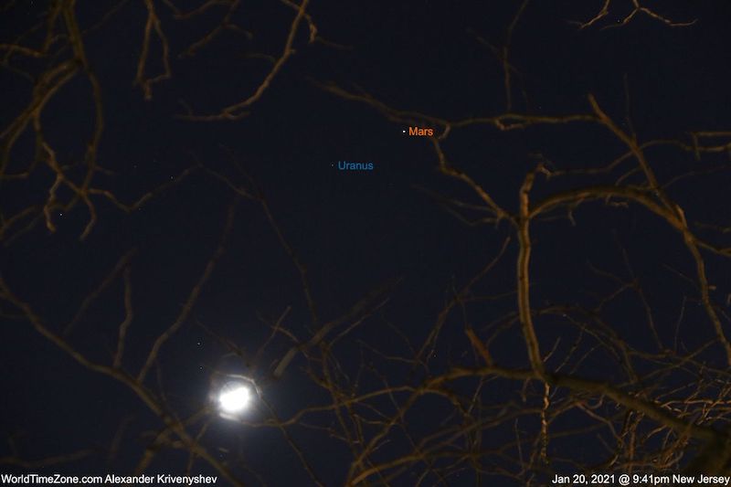 Bright waxing moon in below, Mars and Uranus labeled center top, with branches in the foreground. 
