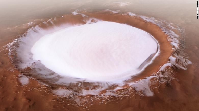 Crater filled with bright white material, in reddish terrain.