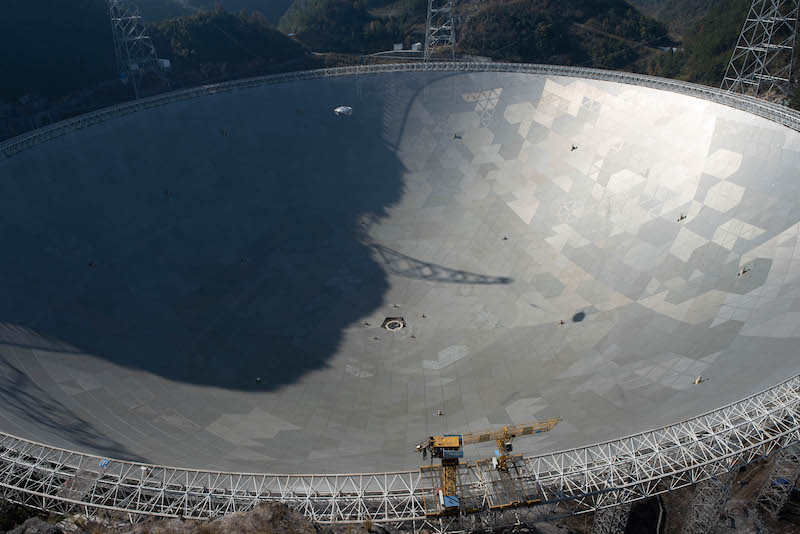 Giant, shining metallic-surfaced dish with shadow in top left.