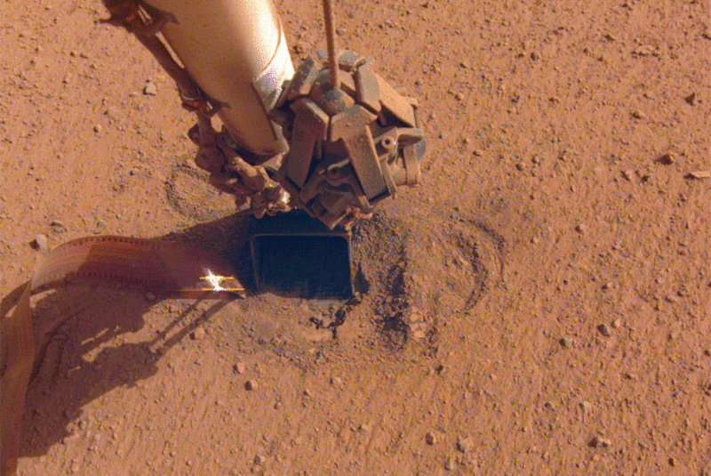 Animation of robot arm repeatedly hitting dusty red ground.