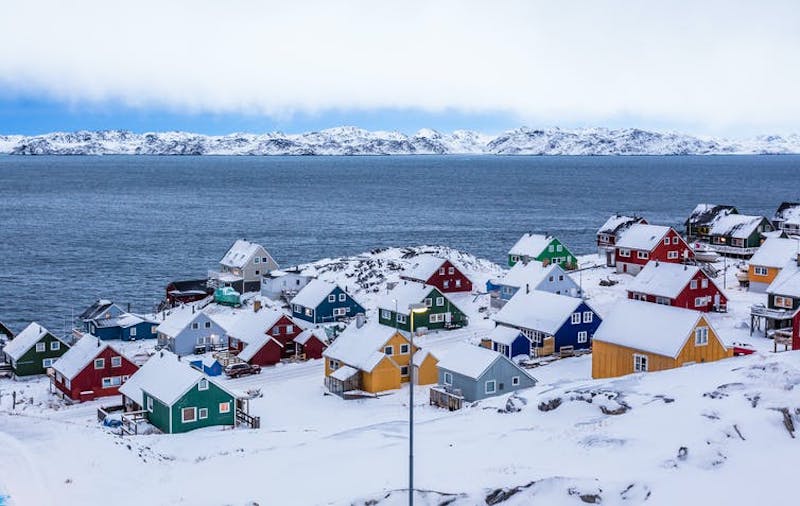 Snow-covered seaside town with 25 small, multicolored houses.