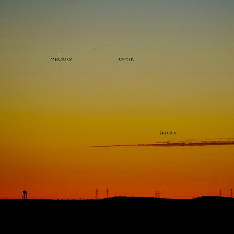 Twlit sky with labeled Mercury, Saturn and Jupiter and sihouetted water tower in far distance.