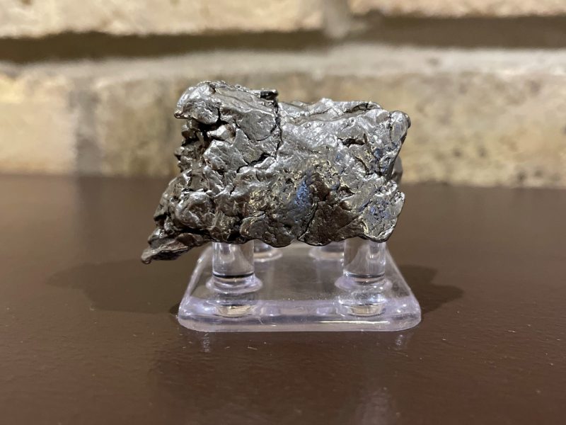 Shiny silver meteorite on a stand.
