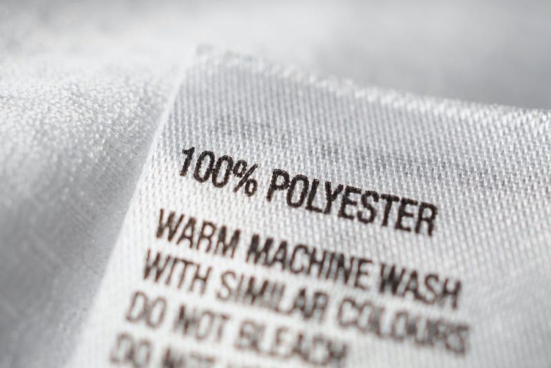 Closeup of a label from a garment saying '100% polyester' with washing instructions.