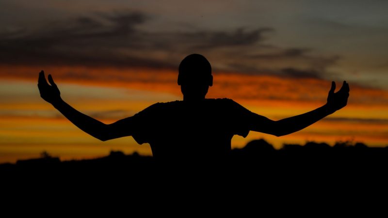 World's population: Silhouette of a man with outspread arms and sunset.
