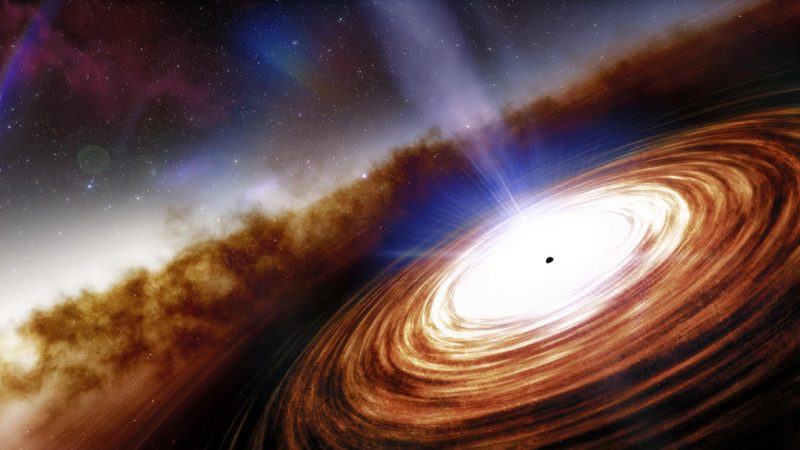 A tiny black dot at the center of a glowing, swirling disk. A jet emanates from the dot perpendicular to the disk.