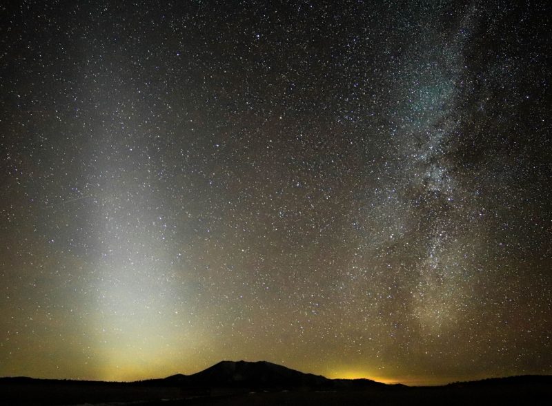 Pyramid-shaped hazy band of zodiacal light, next to a bright section of the starry Milky Way.