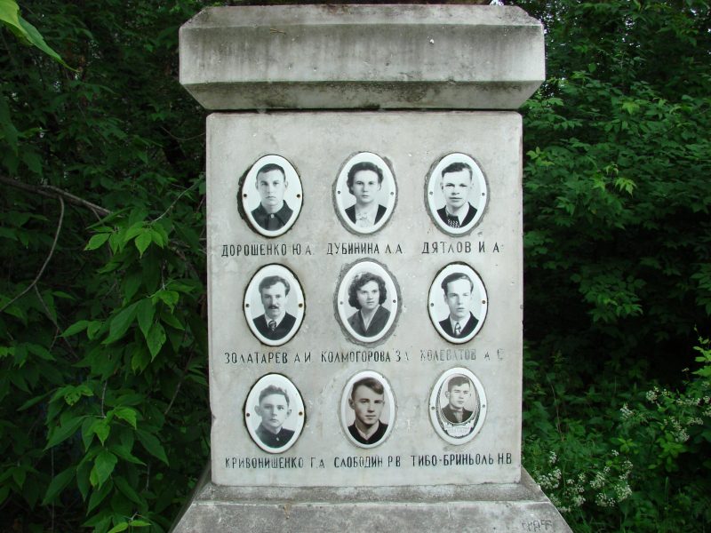 Square stone column with oval photos of 9 people with a name beneath each.