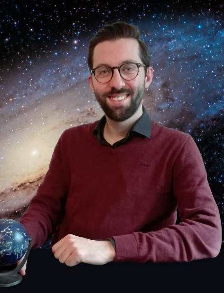 Bearded man with glasses, holding celestial globe, in front of Andromeda galaxy mural.