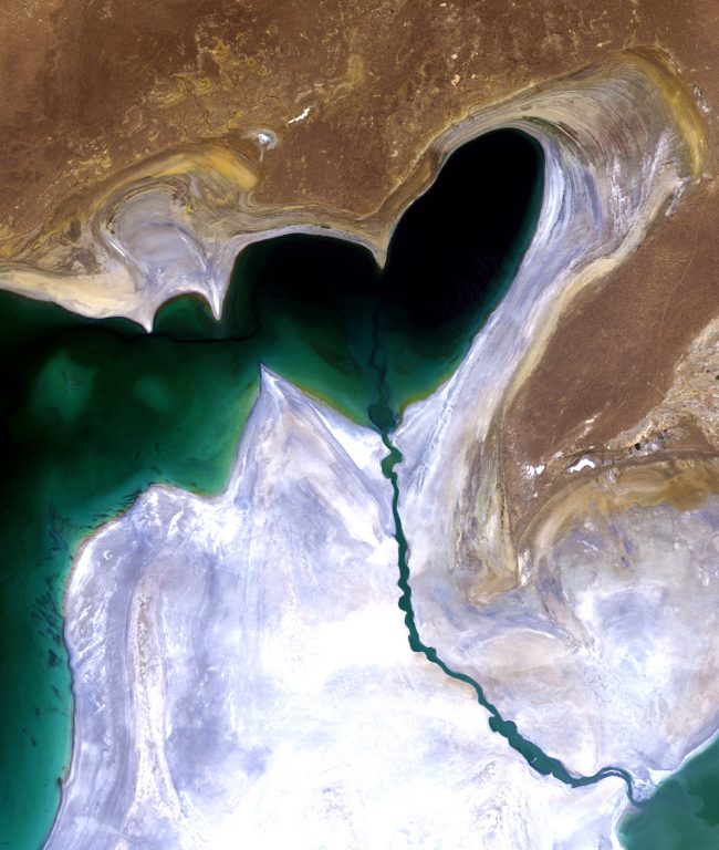 Un lago en forma de corazón de color verde oscuro sobre un fondo marrón y blanco.