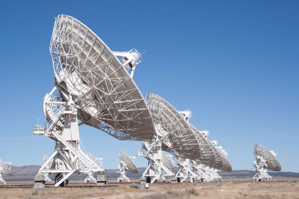 Multiple large white dish-type radio telescopes pointing to the clear blue sky.