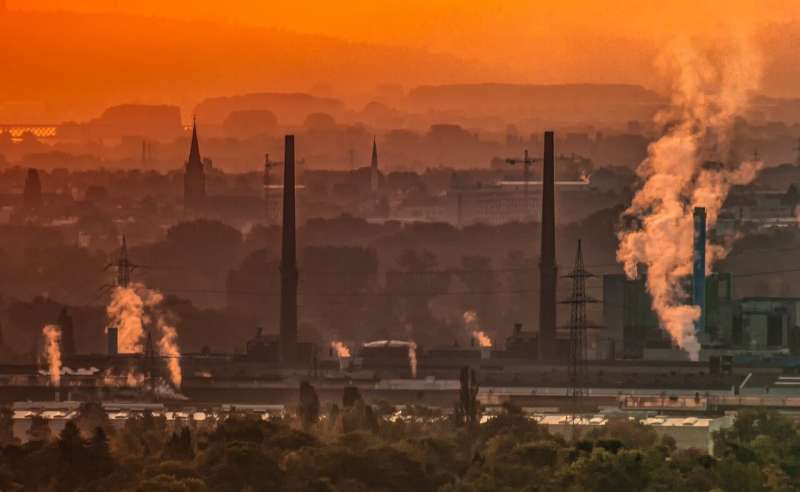 Orange-lit scene of industrial landscape with smokestacks and dirty air.