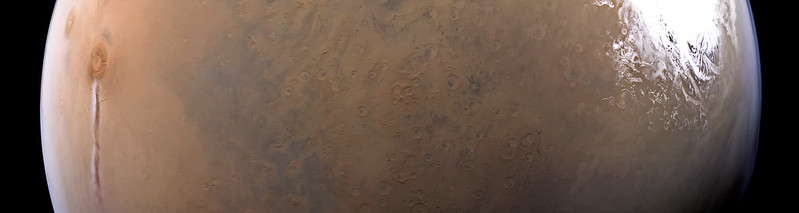 Horizontal slice of Mars with long thin cloud on right and large white patch on right.