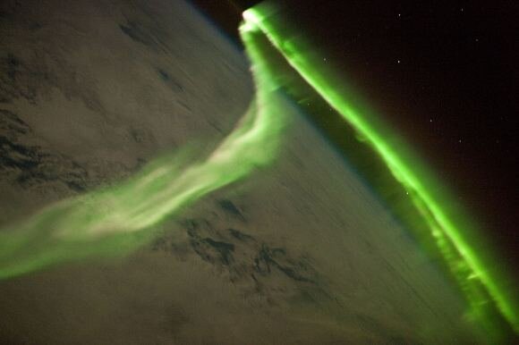 Long, bent green streak above atmosphere as seen from orbital view of Earth.
