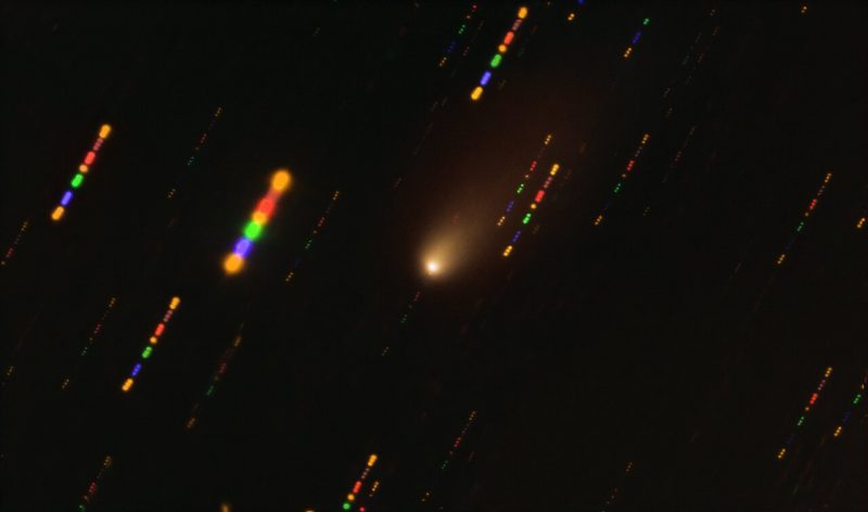 Ball of light with tail surrounded by colorful streaks.