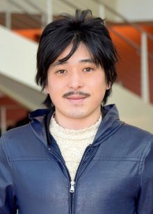 Man with black hair and thin mustache wearing a blue zipper jacket.